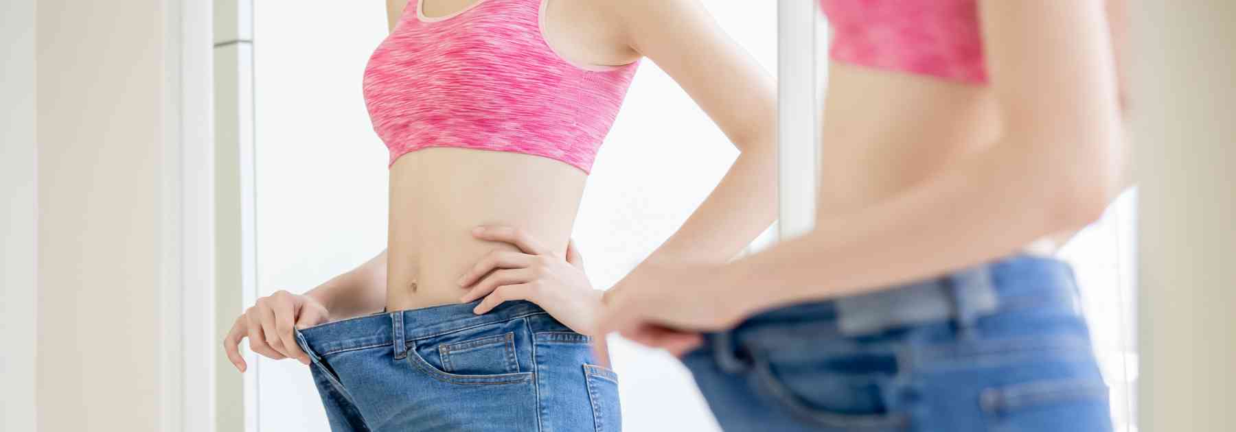 woman looking in mirror wearing jeans too big