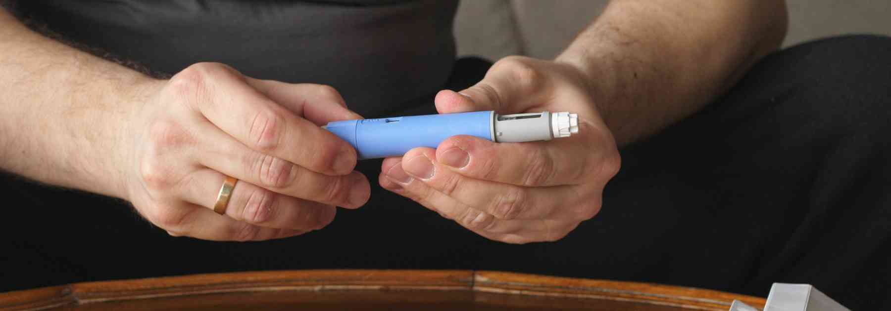 person sitting at table holding weight loss injection