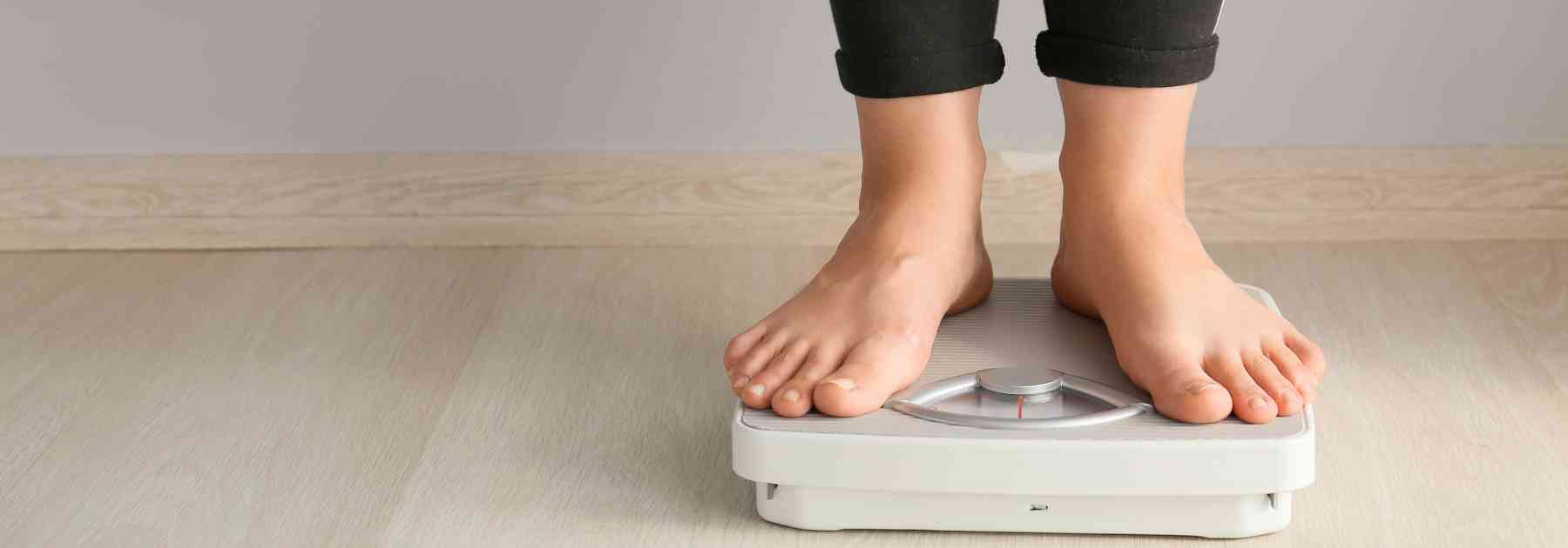 person in black trousers standing on scales