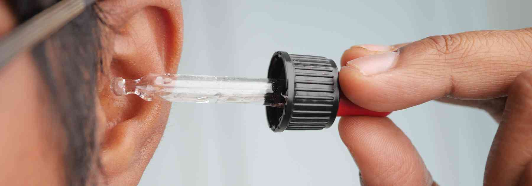 man putting ear drops in ear