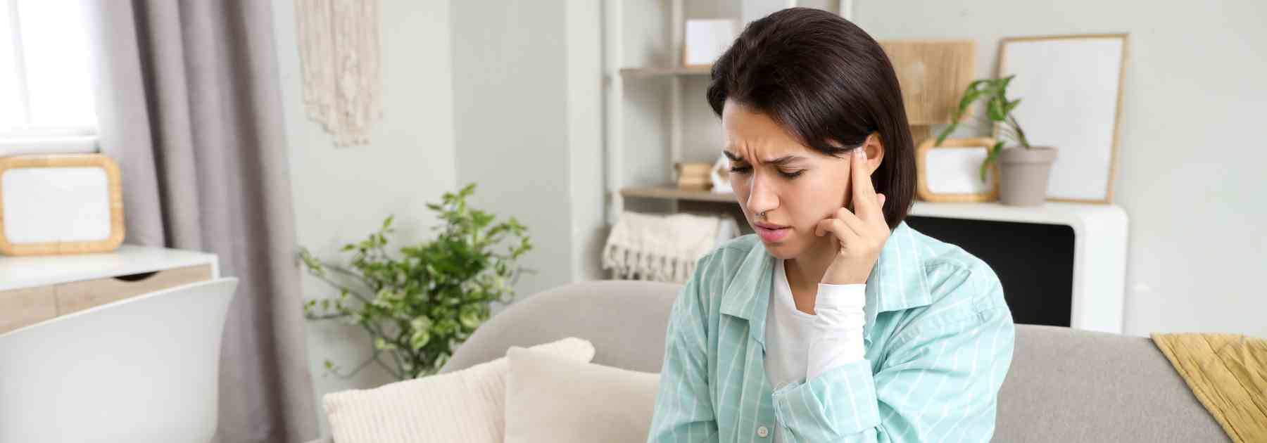 woman pressing her finger on her ear in discomfort