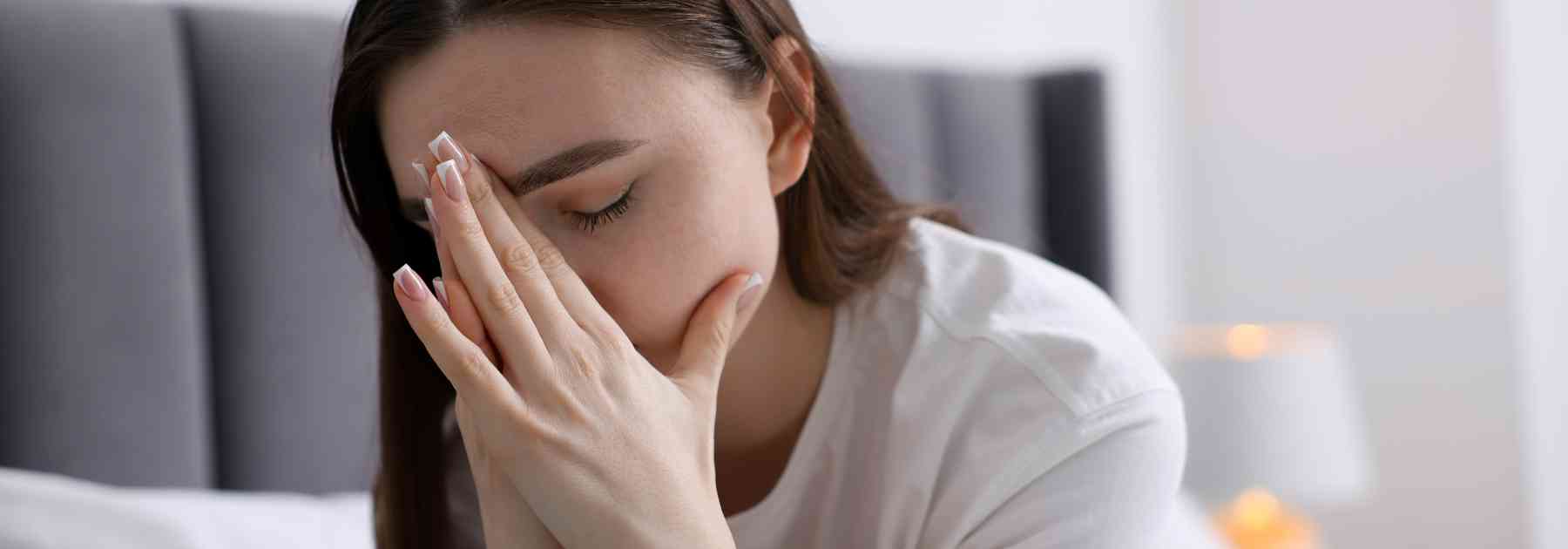 woman sitting on bed looking tired
