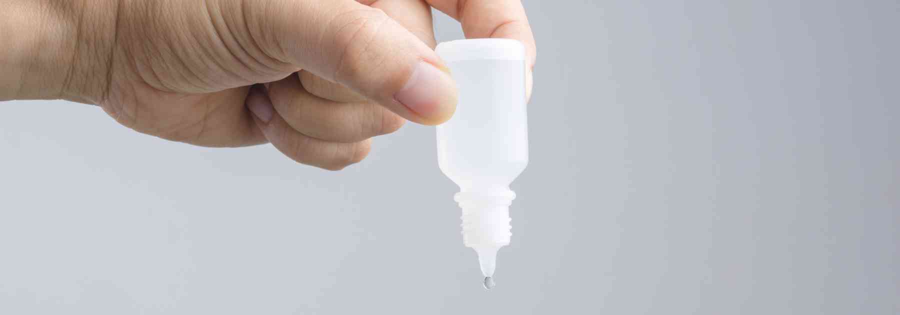 person holding bottle of ear drops upside down