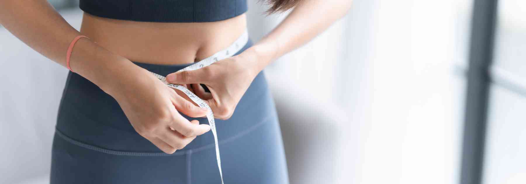 woman in workout gear measuring waist