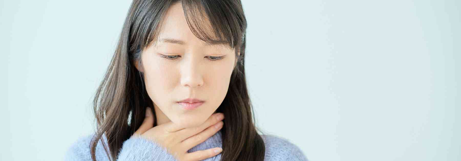 woman clutching her thyroid area
