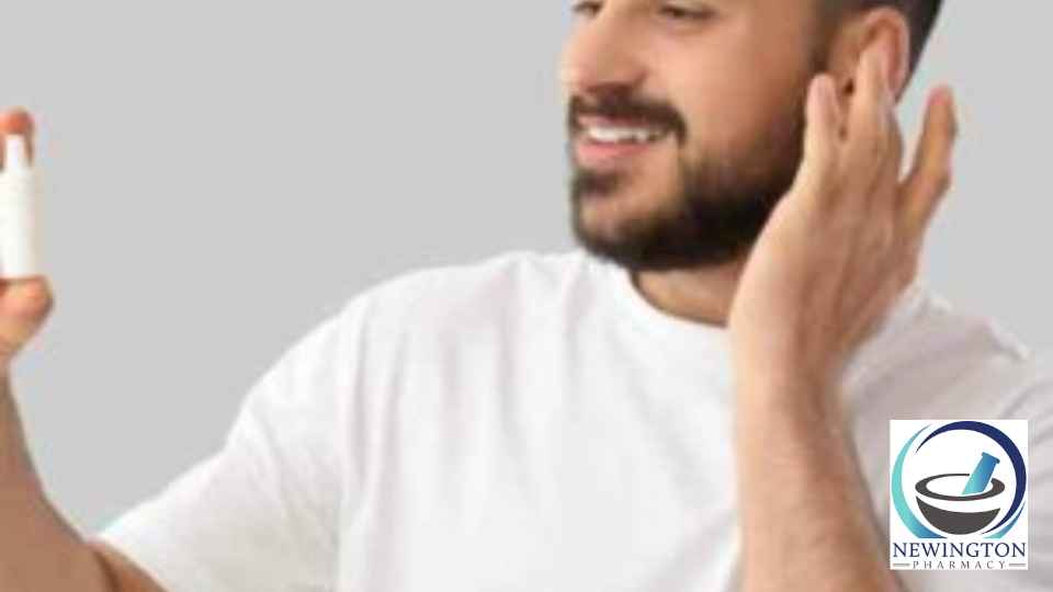man holding ear and bottle of ear drops smiling