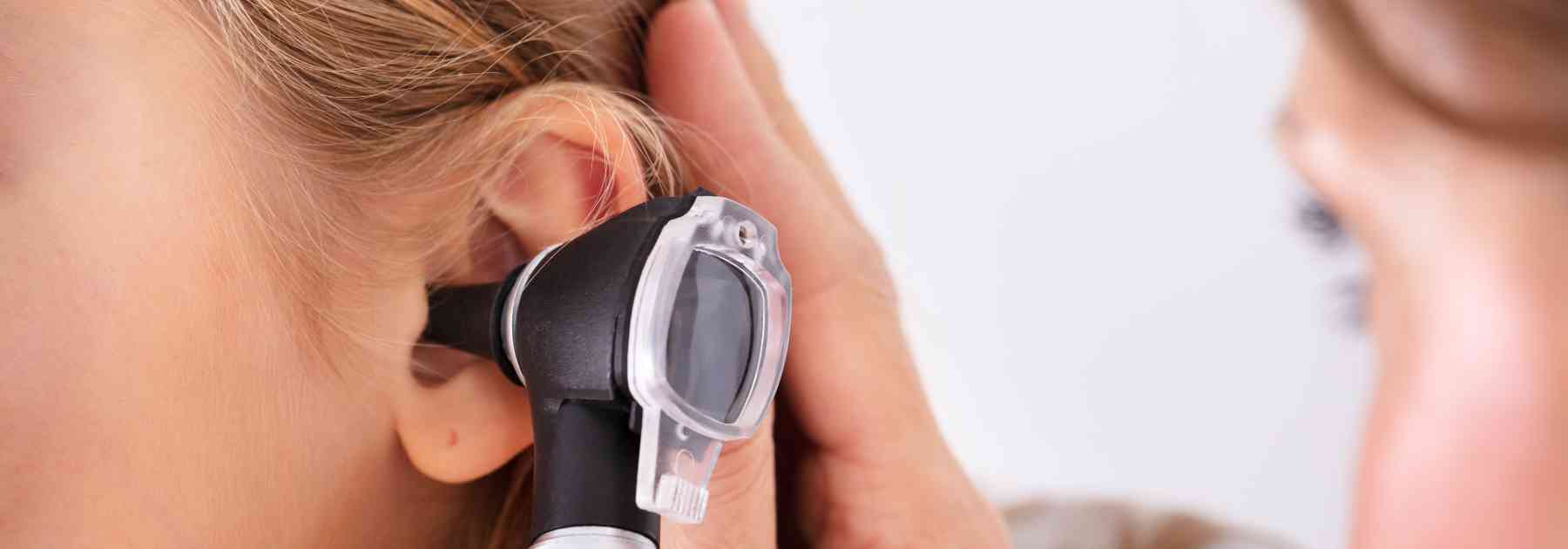 doctor examining ear of female patient