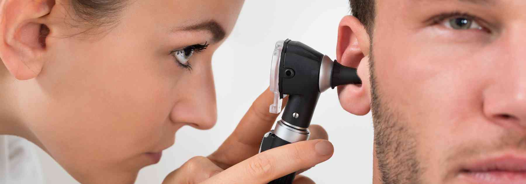 female medical professional examining ear of male patient