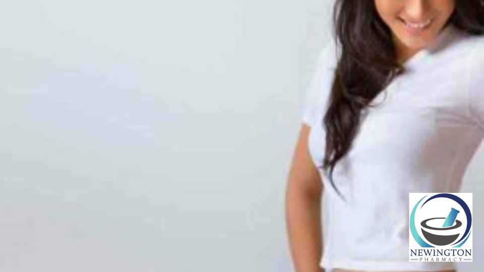 young woman wearing jeans smiling and measuring her waist