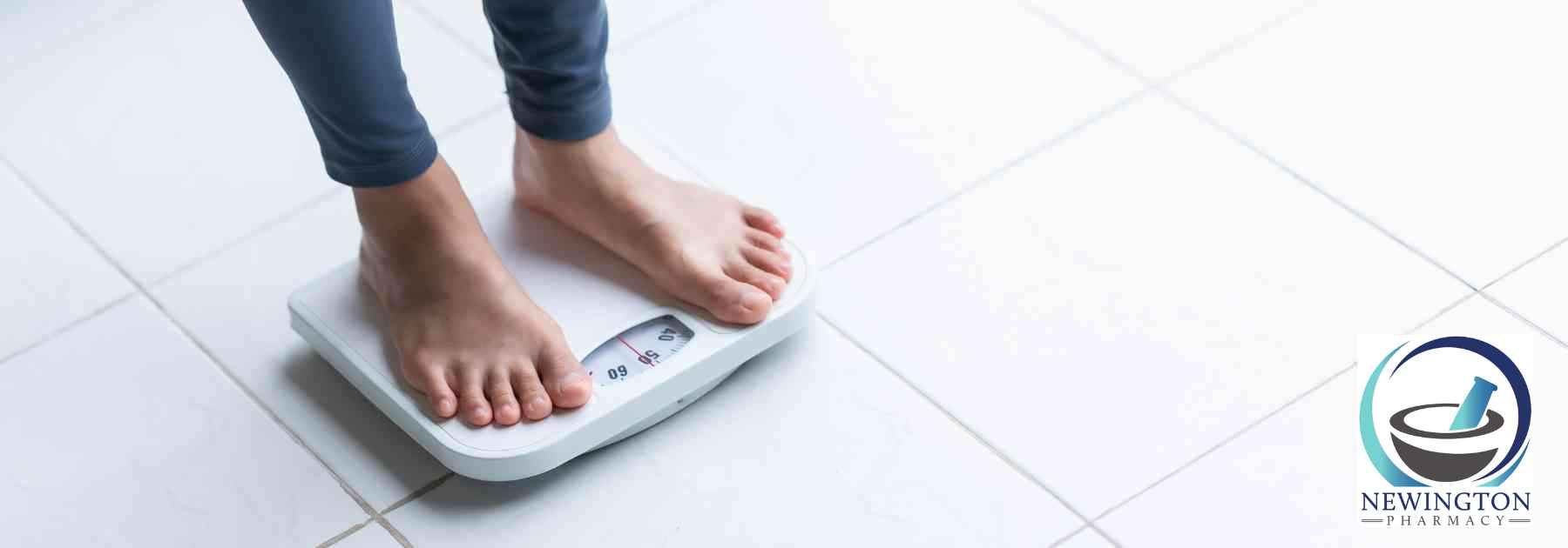 person in grey workout gear and bare feet standing on scales