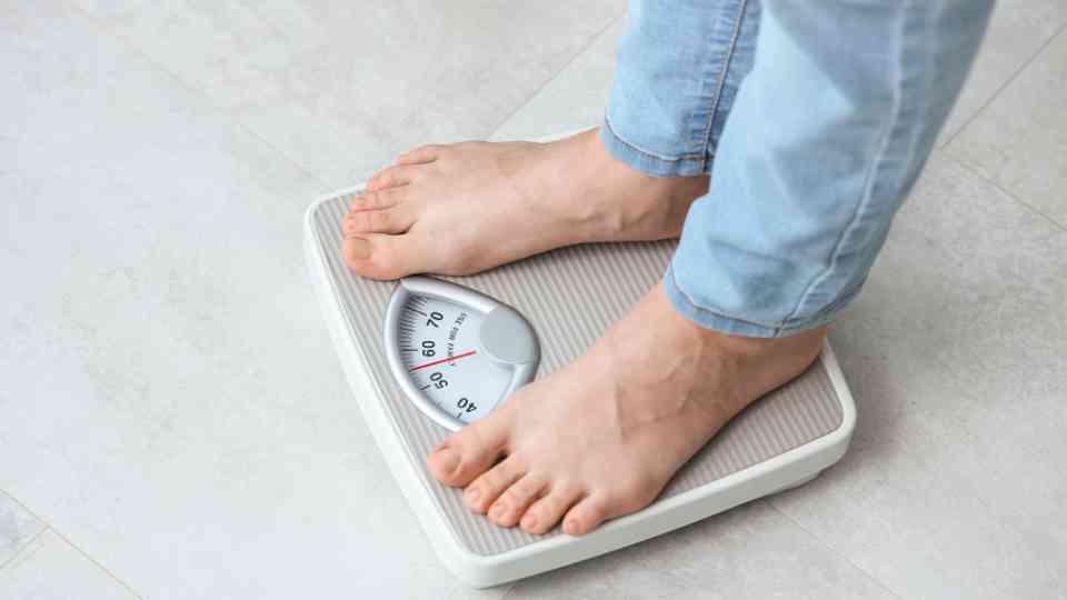 person in blue jeans and bare feet standing on scales