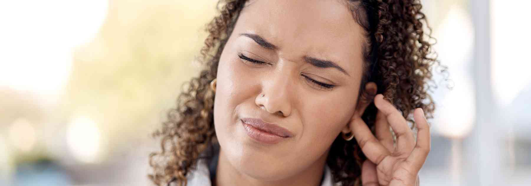 woman holding ear in discomfort