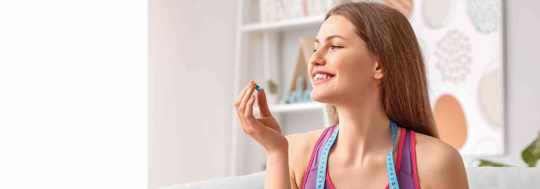 young woman smiling holding weight loss supplement