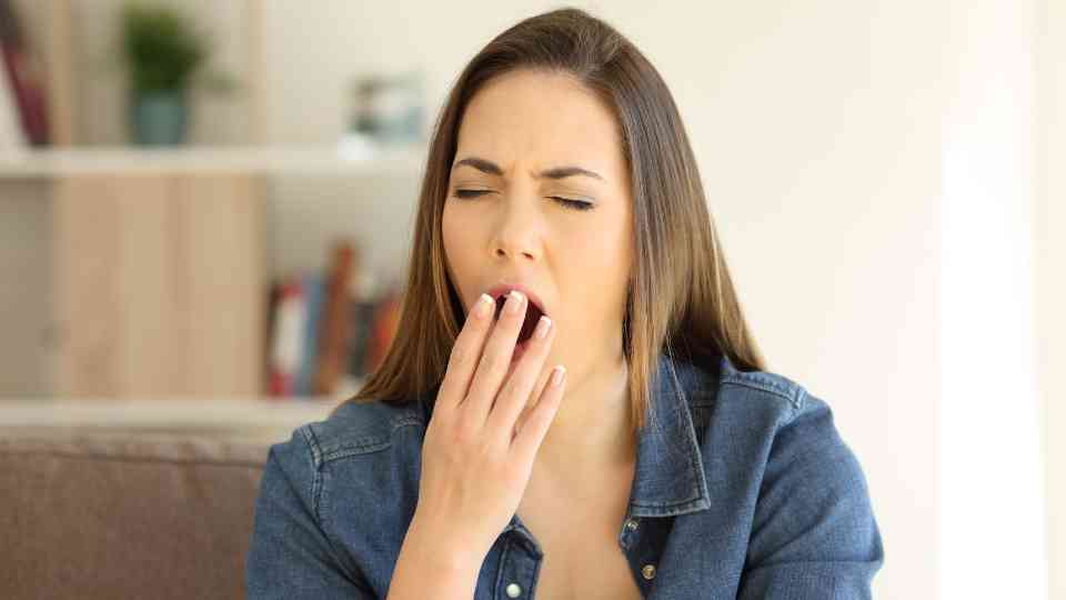 woman sitting on couch yawning