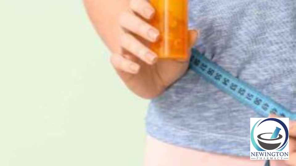 person measuring their waist holding weight loss supplements