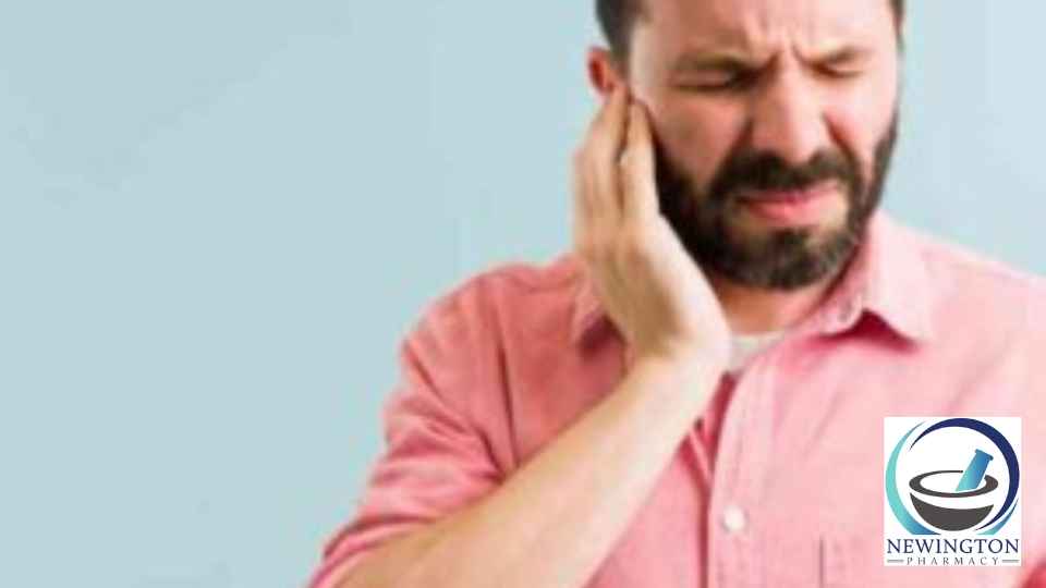 man holding his ear in discomfort on green background