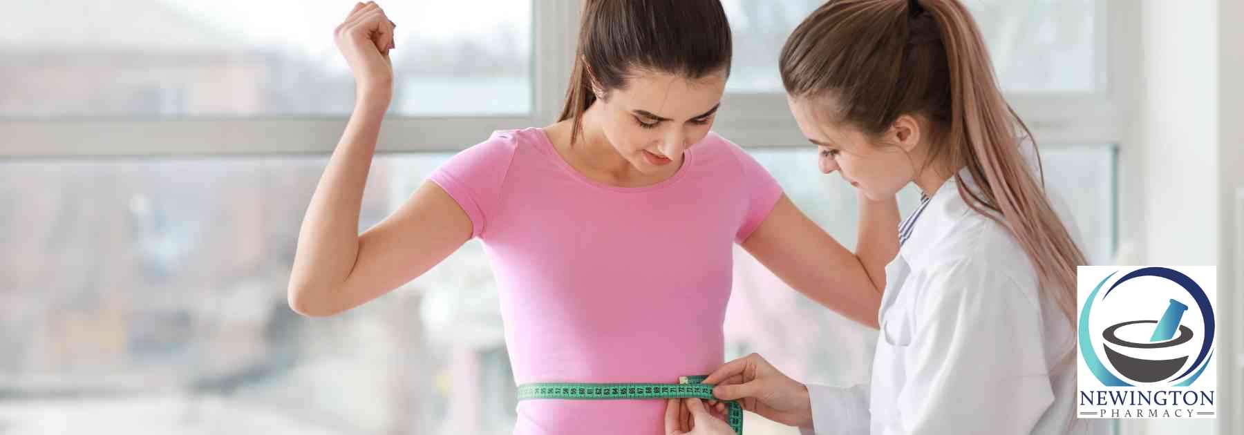 female doctor measuring waist of female patient in pink shirt