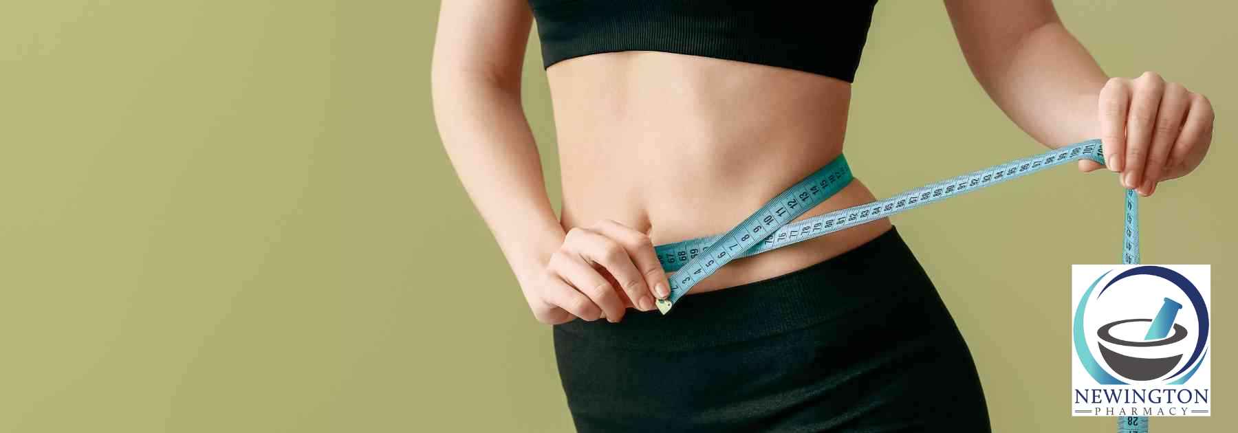 woman in workout gear measuring waist on green background