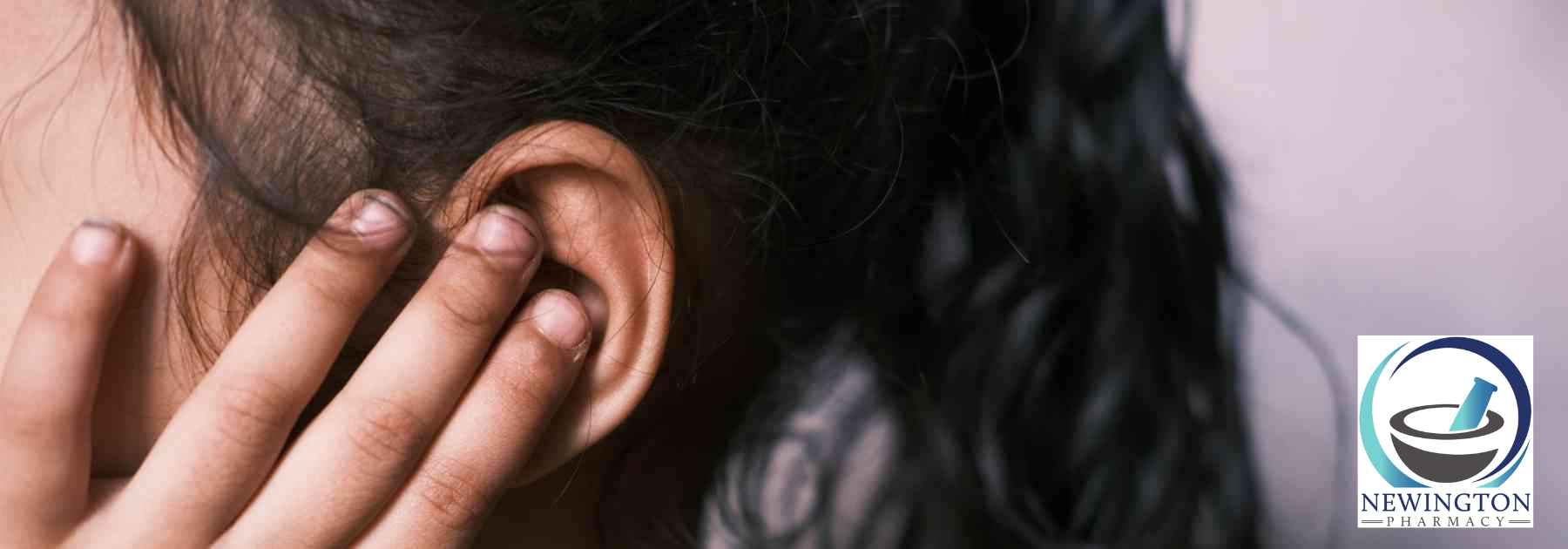 woman with dark hair clutching ear in discomfort