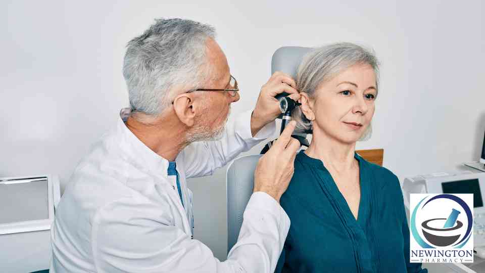 male doctor examining ear of older female patient