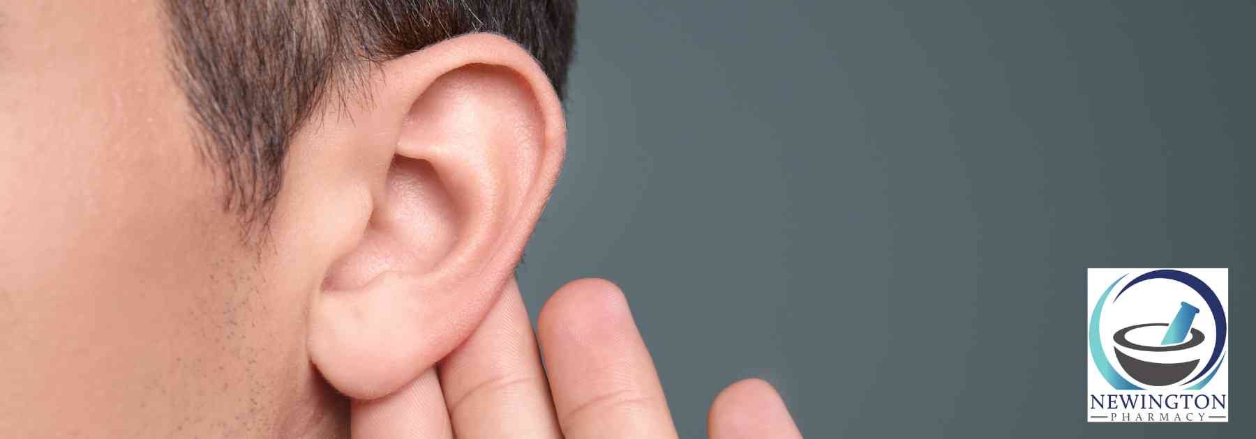 man holding his ear on grey background