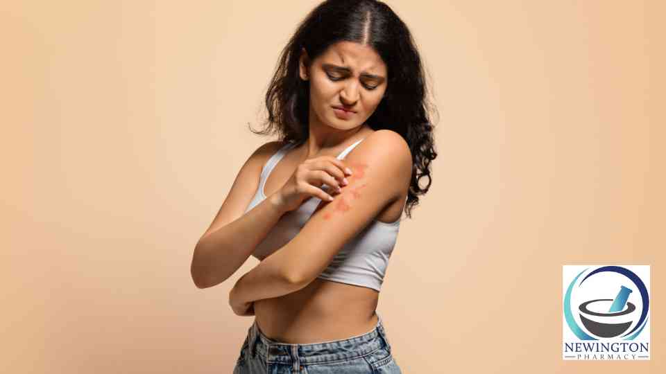 young woman scratching her arm on orange background