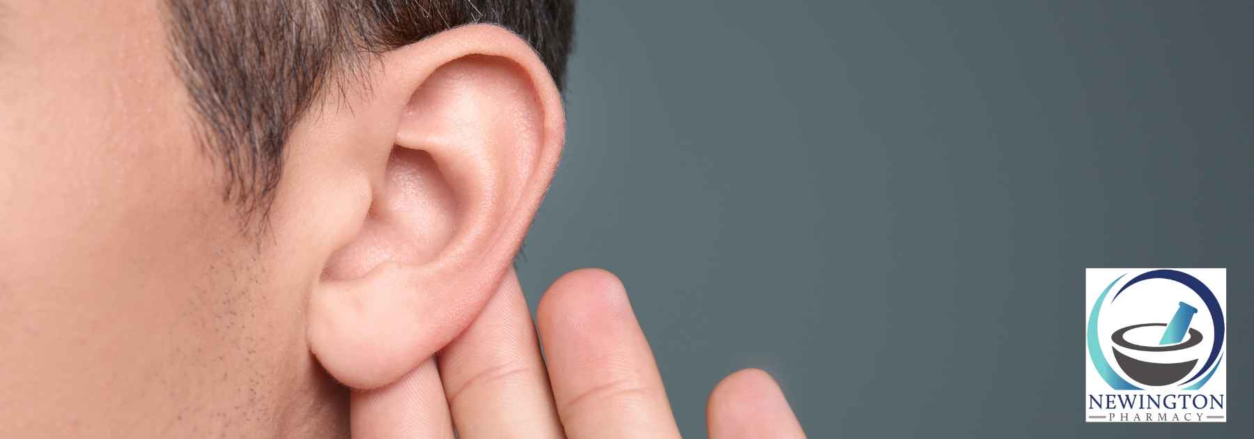 person holding their ear on dark background