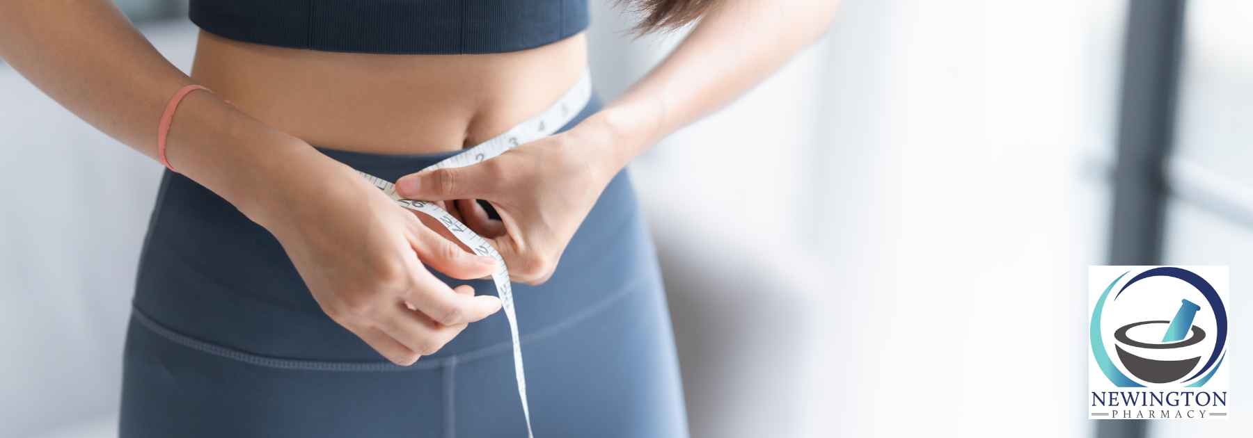 woman in grey workout gear measuring waist