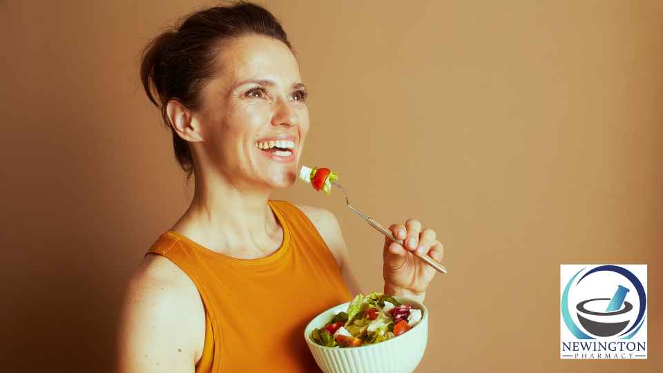 woman eating salad from bowl on orange background