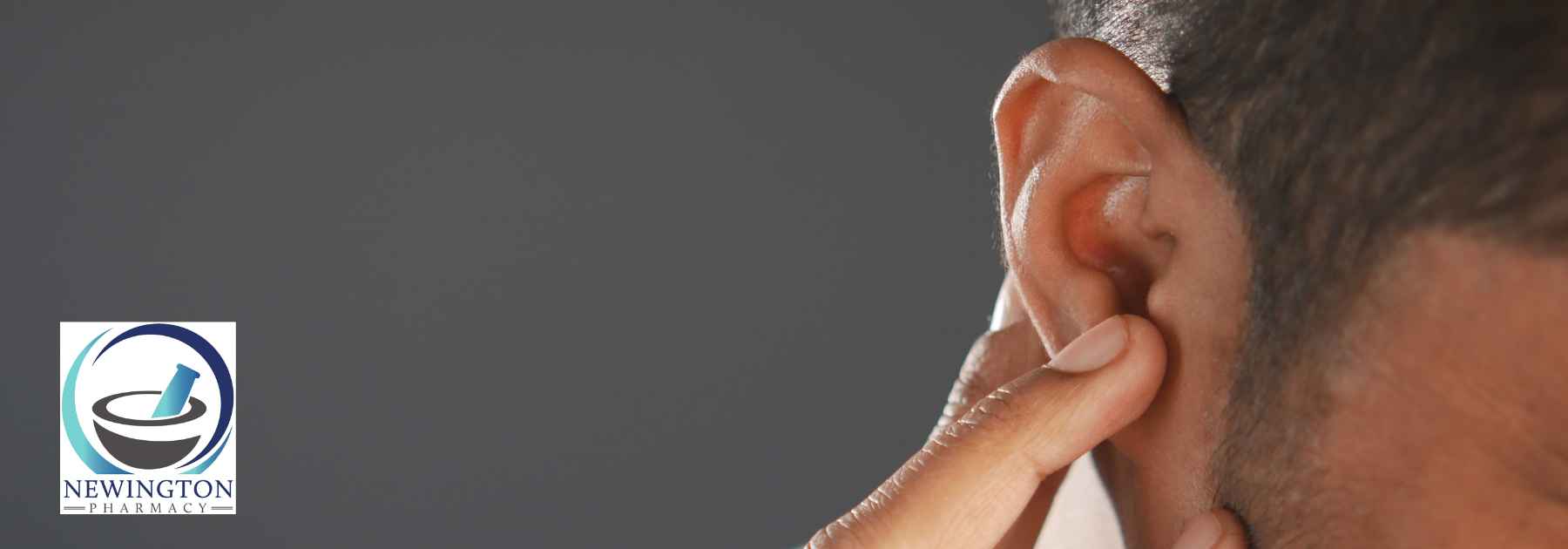 man clutching ear in discomfort on dark background