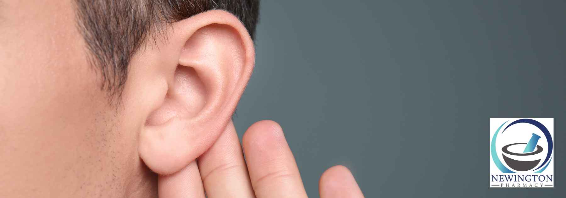 man clutching ear on grey background